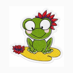 May include: An embroidered patch featuring a green frog with large white eyes and pink cheeks, sitting on a yellow lily pad. The frog has a red flower on its head, and a smaller red flower is positioned on the lily pad to the left side.