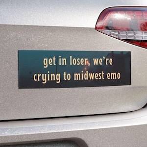 May include: A white ceramic mug with a black handle and the text "But First, Coffee" in a handwritten style. The mug is on a white surface. The mug is approximately 4 inches tall.