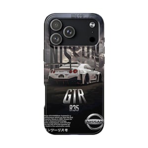 Puede incluir: Funda de teléfono negra con un gráfico de coche deportivo Nissan GTR R35 blanco. La funda tiene un borde negro e incluye el logotipo de Nissan y el texto "GTR R35". El fondo tiene un cielo nublado.