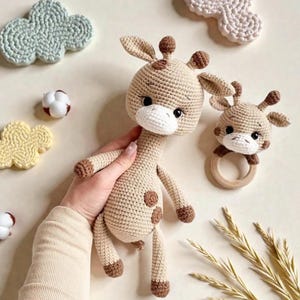 Könnte beinhalten: Gehäkeltes Giraffen-Spielzeug- und Rassel-Set in Beige und Braun. Die Giraffe hat einen langen Hals, kleine Ohren und braune Flecken. Die Rassel hat einen Giraffenkopf, der an einem Holzring befestigt ist. Dekorative Wolken und andere Häkelartikel befinden sich im Hintergrund.