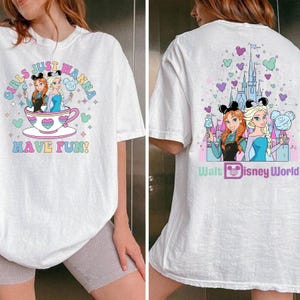 May include: White t-shirt featuring a colorful graphic of Anna and Elsa from Frozen, with the text "GIRLS JUST WANNA HAVE FUN!" on the front. The back of the shirt has a castle graphic and the words "Walt Disney World".