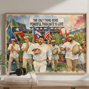 May include: A framed watercolour print depicting a group of men marching with flags and musical instruments. The text at the top reads, "THE ONLY THING MORE POWERFUL THAN HATE IS LOVE." The men are wearing white shirts and hats. The print is displayed on a wooden surface.