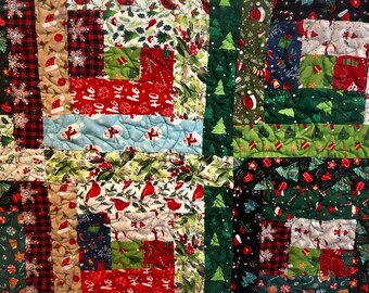 May include: A patchwork quilt with a Christmas theme. The quilt features squares of fabric with various holiday patterns, including Christmas trees, holly, snowflakes, and the words "Ho Ho Ho". The color palette includes red, green, white, and blue.