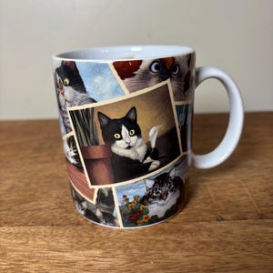 May include: White ceramic mug featuring a collage of cat portraits. The mug showcases various cat breeds and poses, with a white handle. The design includes a black and white cat, a Siamese cat, and other felines, set against a light background.