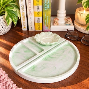 May include: A circular white tray with a green marbled pattern, divided into three sections. A small, matching green and white scalloped dish sits in the center top section. The tray has a smooth finish and a raised outer edge.