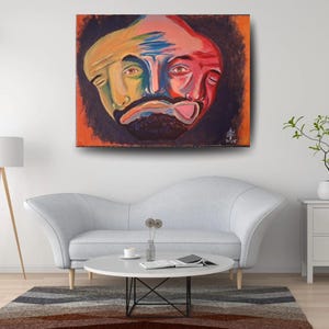 May include: A rectangular canvas painting featuring a stylised, multi-faceted human face rendered in vibrant shades of yellow, blue, and red. The face is set against a dark, textured background with an orange border, signed and dated 2015.