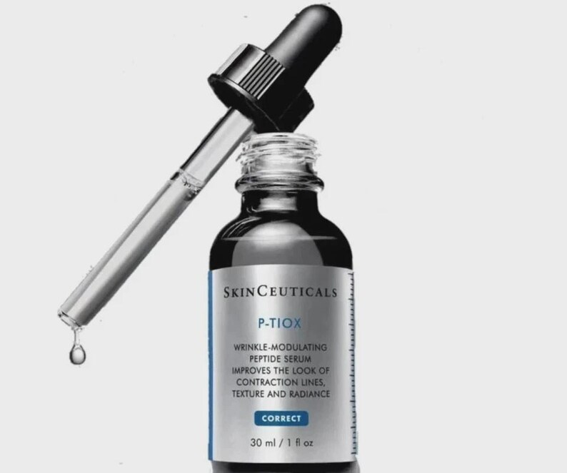May include: A skincare product bottle with a dropper. The bottle is dark with a white and blue label that reads "SKINCEUTICALS P-TIOX WRINKLE-MODULATING PEPTIDE SERUM." The dropper is partially inserted, with a drop of serum falling. The bottle contains 1 fl oz of product.