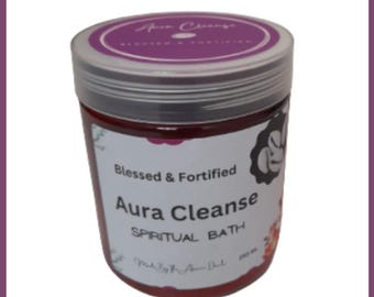May include: A cylindrical jar with a silver lid and a purple label that reads "Aura Cleanse Spiritual Bath." The jar contains a reddish liquid and has a white label with the words "Blessed & Fortified."