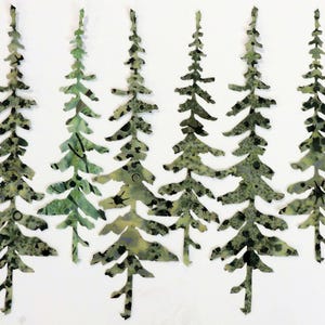 May include: Seven green and black patterned paper cutouts of pine trees. The trees are arranged in a row, with the tallest tree in the center.