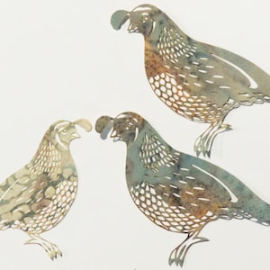 May include: Three paper cutouts of quail birds in shades of brown, green, and white. The birds are facing different directions and have intricate details.