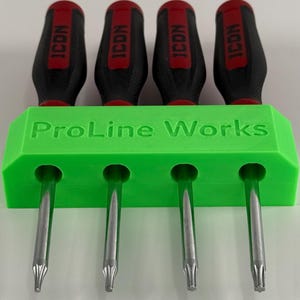 Könnte beinhalten: Ein Satz von vier Schraubendrehern mit schwarzen und roten Griffen, die in einem hellgrünen Halter gehalten werden. Die Schraubendreher haben silberne Spitzen und das Wort "ICON" ist auf den Griffen sichtbar. Der Halter trägt den Text "ProLine Works".