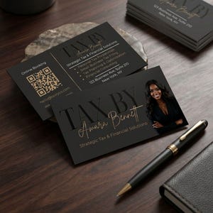 May include: Black business cards with gold lettering and a photo of a woman. The cards read "TAX BY Amara Bennett" and list services like tax preparation and financial consulting. A pen and small notebook are also visible.