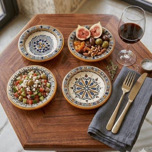May include: Four patterned ceramic bowls, each with a different filling, arranged on a wooden table. One bowl contains figs, olives, and nuts. A wine glass, cutlery, and a napkin are also present. The bowls have blue and yellow patterns.
