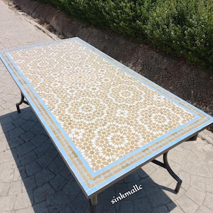 May include: A rectangular mosaic tile table with a light blue border and black metal legs. The tabletop features a repeating star pattern in beige and white. The table measures approximately 152 cm long and 76 cm wide.
