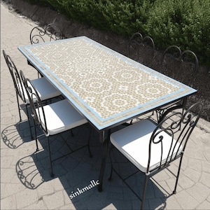 May include: Outdoor dining set featuring a rectangular table with a mosaic tile top in beige and blue, and four wrought iron chairs with white cushions. The table is approximately 60 inches long.