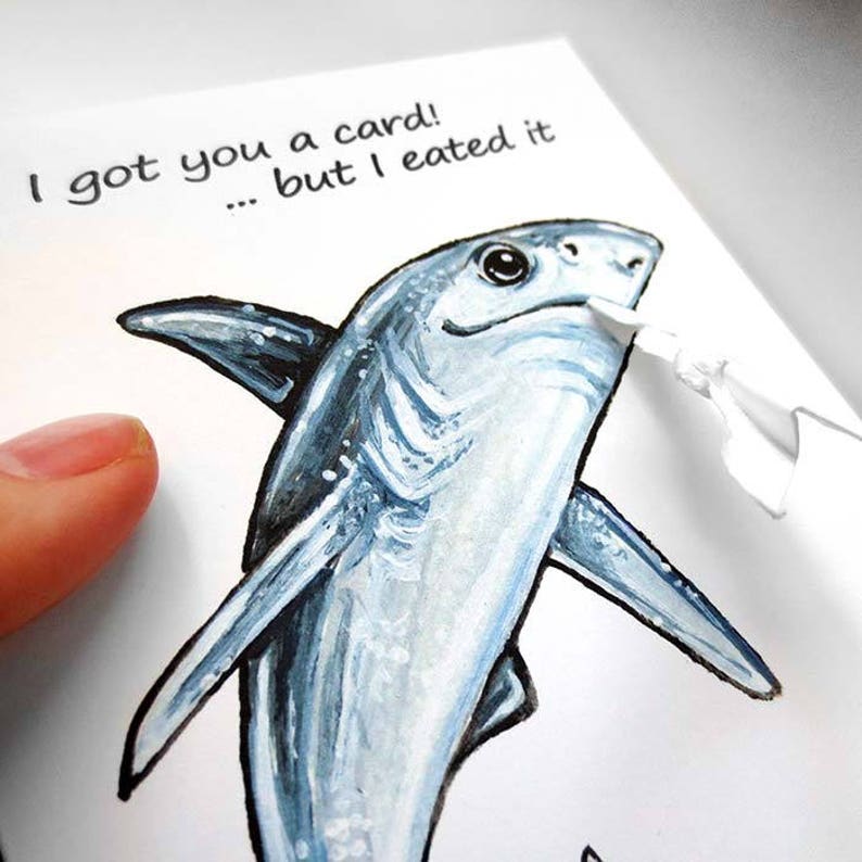 May include: A greeting card with a hand-painted illustration of a blue shark. The card reads "I got you a card! ... but I ate it."