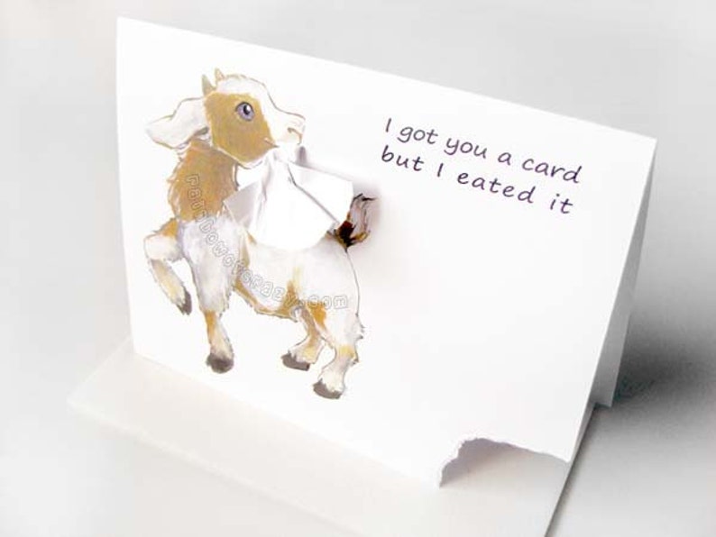 May include: A white greeting card with a 3D illustration of a goat. The goat is brown, white, and tan with blue eyes. The card reads, "I got you a card but I eated it."