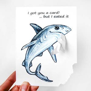 May include: A white card with a blue shark illustration. The card says "I got you a card! ... but I ate it."