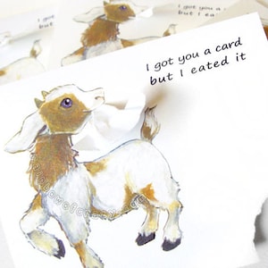 May include: A whimsical greeting card featuring a cartoon goat with brown and white markings. The card has the text "I got you a card but I eated it". The card is torn, with additional goat illustrations in the background.