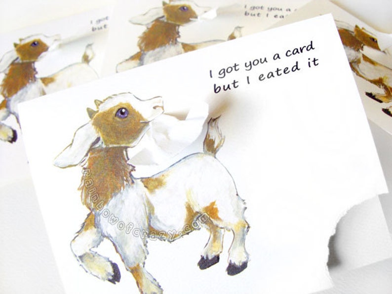 May include: A whimsical greeting card featuring a cartoon goat with brown and white markings. The card has the text "I got you a card but I eated it". The card is torn, with additional goat illustrations in the background.