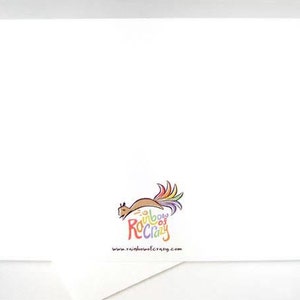 May include: A white greeting card with the "Rainbow of Crazy" logo, featuring a squirrel with a rainbow tail. The website address www.rainbowofcrazy.com is printed below the logo. The card is on a white surface.