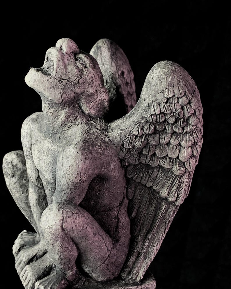 K&ouml;nnte beinhalten: Verwitterte, graue Gargoyle-Statue mit gro&szlig;en, detaillierten Fl&uuml;geln und offenem Mund. Die Skulptur befindet sich in sitzender Position, mit sichtbaren Rissen, die zu ihrem gealterten Aussehen beitragen. Der Hintergrund ist schwarz.