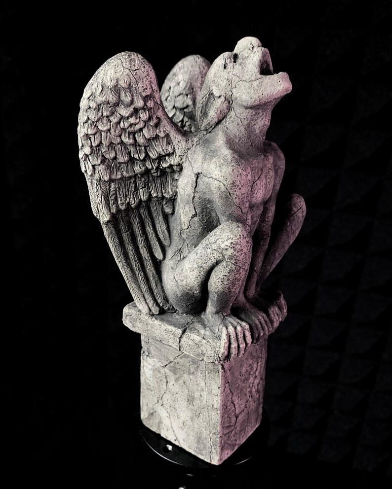 K&ouml;nnte beinhalten: Graue Stein-Wasserspeier-Statue mit gro&szlig;en, detaillierten Fl&uuml;geln, die auf einem quadratischen Sockel sitzt. Die Statue hat einen offenen Mund und eine verwitterte, rissige Textur. Der Hintergrund ist schwarz.