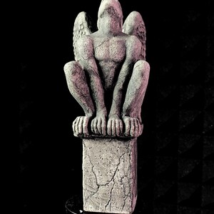 K&ouml;nnte beinhalten: Eine graue Gargoyle-Statue mit ausgebreiteten Fl&uuml;geln, die auf einem verwitterten Steinsockel sitzt. Die Statue hat einen muskul&ouml;sen Torso und blickt nach oben. Die Statue ist etwa 25 cm hoch.