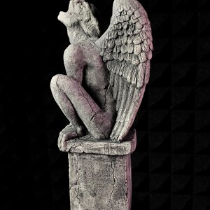 K&ouml;nnte beinhalten: Graue Stein-Wasserspeier-Statue mit gro&szlig;en, detaillierten Fl&uuml;geln, die auf einem quadratischen Sockel sitzt. Die Statue befindet sich in einer hockenden Position, mit zur&uuml;ckgeneigtem Kopf und offenem Mund. Die Skulptur hat ein verwittertes, gealtertes Aussehen.