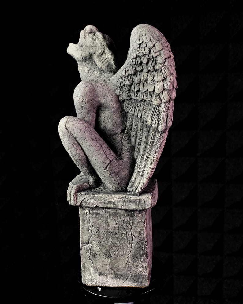 K&ouml;nnte beinhalten: Graue Stein-Wasserspeier-Statue mit gro&szlig;en, detaillierten Fl&uuml;geln, die auf einem quadratischen Sockel sitzt. Die Statue befindet sich in einer hockenden Position, mit zur&uuml;ckgeneigtem Kopf und offenem Mund. Die Skulptur hat ein verwittertes, gealtertes Aussehen.