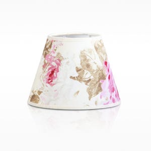 Könnte beinhalten: Ein konischer Lampenschirm aus cremefarbenem Stoff, der mit einem Blumenmuster in gedeckten Braun- und Beigetönen sowie leuchtendem Pink verziert ist. Der Lampenschirm hat eine klassische Form mit glatten, sauber geschnittenen Kanten.