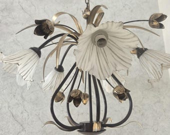 Op de afbeelding: Een bloemvormige kroonluchter met meerdere witte, klokvormige glazen kappen met geschulpte randen en donkere metalen accenten. Het armatuur bevat slanke, gebogen metalen stelen en kleinere, gesloten metalen bloemknoppen in een bronzen afwerking.