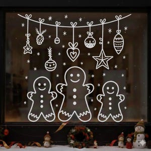 Puede incluir: Adhesivos blancos de ventana navideños con hombres de jengibre y adornos festivos. El diseño incluye decoraciones colgantes como estrellas, corazones y bolas, junto con copos de nieve que caen. Una alegre decoración navideña para ventanas.