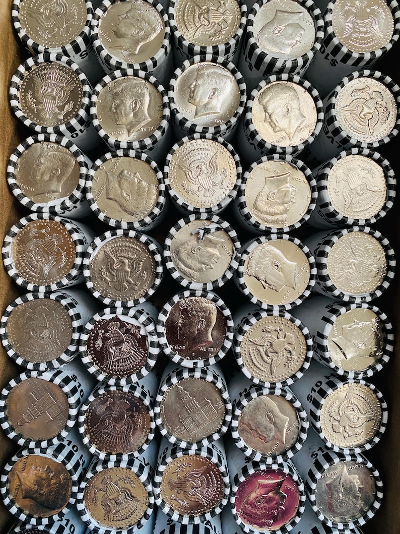 May include: A collection of rolled United States half-dollar coins arranged in a grid. Each paper roll is secured with black and white striped tape and displays either the profile of John F. Kennedy or the presidential seal on the visible end.