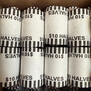 May include: Eight cylindrical coin rolls arranged in two rows of four. Each white paper wrapper features black vertical stripes at the ends and the printed text $10 HALVES, indicating the contents are ten dollars in half-dollar coins.