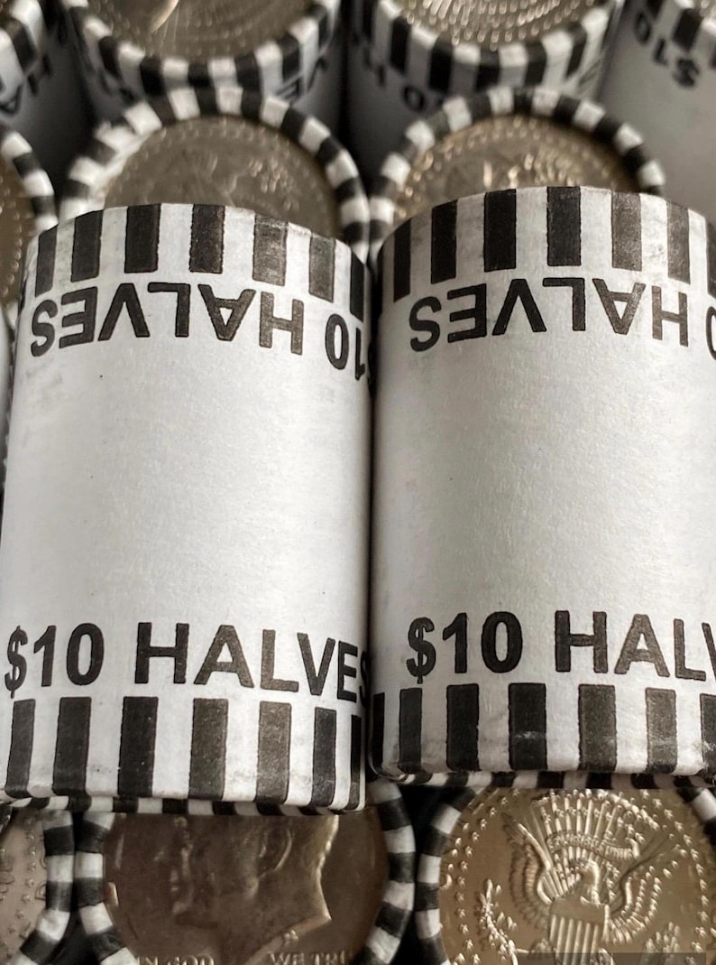 May include: Two cylindrical paper coin rolls containing half-dollar coins, each labeled $10 HALVES with black and white striped edges. The rolls are arranged in a grid, with additional rolls visible in the background and silver coins partially exposed.