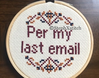 May include: A white embroidery hoop with a cross-stitch design that reads "Per my last email". The design is in shades of burgundy, orange, and blue.