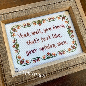 Pode incluir: Um bordado de ponto de cruz enquadrado com fundo branco e uma borda floral marrom, verde e laranja. O texto diz "Yeah, well, you know, that's just like, your opinion, man." O canto inferior direito da moldura tem o texto "StephXstitch".