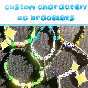 May include: Custom character bracelets with white letter beads spelling out names and phrases. The bracelets are in various colors, including green, blue, and black, with decorative star-shaped charms. The text "custom character/ oc bracelets" is at the top.