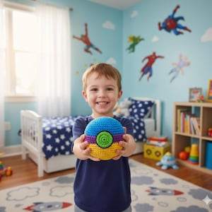 May include: A child holds a colorful, crocheted ball. The ball features blue, purple, yellow, and green sections. The child is in a room with superhero wall decals and a star-patterned rug.