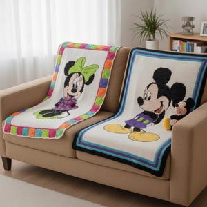 Puede incluir: Dos mantas de ganchillo con los personajes de Disney Minnie Mouse y Mickey Mouse. La manta de Minnie Mouse tiene un borde colorido y un lazo verde. La manta de Mickey Mouse tiene un borde negro, azul y blanco. Un peluche de Mickey Mouse está en el sofá.