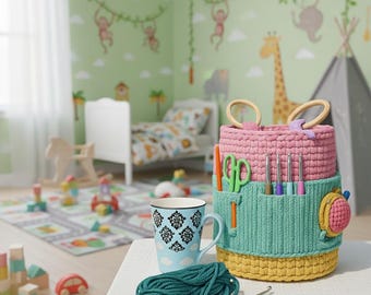 Puede incluir: Un organizador de ganchillo de varios niveles en rosa, turquesa y amarillo, con asas de madera. Contiene tijeras, ganchillos y otras herramientas. Una taza azul con un diseño floral y un ovillo de lana turquesa sugieren un tema de manualidades.