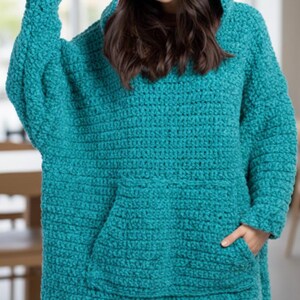 Puede incluir: Una manta con capucha de crochet turquesa con un bolsillo de canguro y una capucha con orejas rosas. La manta de gran tama&ntilde;o est&aacute; dise&ntilde;ada para ser usada, ofreciendo calidez y comodidad. Dise&ntilde;o acogedor y hecho a mano.