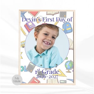 Könnte beinhalten: Gerahmter Druck mit einem lächelnden Kind in einem blauen Hemd, mit dem Text "Devin's First Day of 1st Grade 2026-2027" in Blau. Der Hintergrund ist weiß mit farbenfrohen Illustrationen zum Thema Schule, darunter Bücher, Bleistifte und ein Rucksack.