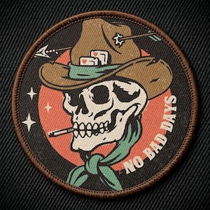 May include: Round patch featuring a skull wearing a cowboy hat with an arrow through it, a green bandana, and a cigarette. The patch has the words "NO BAD DAYS" in white text.