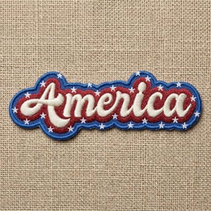 May include: Embroidered patch with the word "America" in white script lettering. The patch has a red interior with white stars, a blue border, and is set against a tan fabric background.