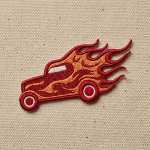 May include: Embroidered patch featuring a stylized red hot rod car engulfed in flames. The car has a white window and red wheels with white centers. The flames are a mix of orange and red, creating a dynamic design.