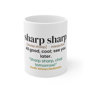 May include: A white ceramic mug featuring black, brown, green, and gold text that defines the phrase sharp sharp as an interjection meaning all good, cool, see you later, including an example sentence and the words South African Dictionary.