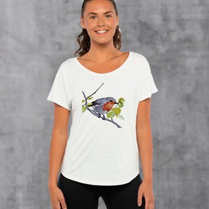 Puede incluir: Camiseta blanca con una ilustraci&oacute;n de acuarela de un petirrojo posado en una rama con hojas verdes.