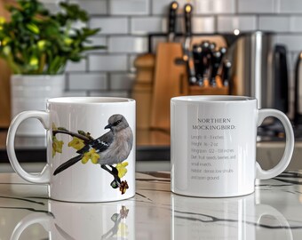 Puede incluir: Taza de cerámica blanca con una ilustración colorida de un  'Northern Mockingbird' posado en una rama con flores amarillas. La taza tiene texto que dice "NORTHERN MOCKINGBIRD: Longitud 8 - 11 pulgadas, Peso 1.6 - 2 oz, Envergadura 12.2 - 11.8 pulgadas, Dieta: Fruta, semillas, bayas e insectos pequeños, Hábitat: Arbustos bajos densos y terreno abierto."